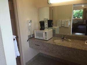 a bathroom with a sink and a mirror and a microwave at Belmont Inn and Suites in Hampton