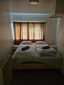 a bed with two pillows in front of a window at Frozen Arctic Waterfall Appartment in Tromsø