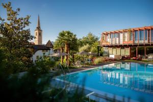 a large swimming pool next to a building with a church at Kati`s Guesthouse-Zentral in Kaltern in Caldaro