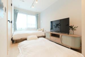 a living room with a flat screen tv and a bed at RIZOTIA Hakusan by Tranova in Tokyo