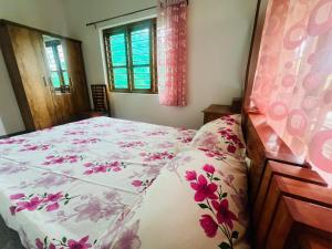 a bedroom with a bed with a floral bedspread at Misty Homes Stay in Napoklu
