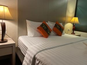 a bedroom with a bed with white sheets and orange pillows at A Plus Deluxe Hotel in Ko Lipe