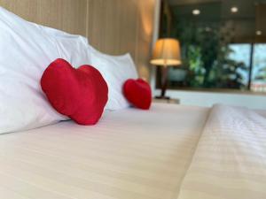 two red pillows with hearts on a bed at A Plus Deluxe Hotel in Ko Lipe