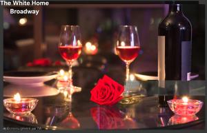 two glasses of wine on a table with candles at The White Home Broadway Love Room in Châteauroux