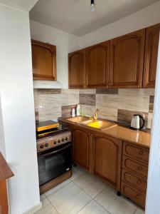 a kitchen with wooden cabinets and a stove top oven at Qafoku GuestHouse in Çorovodë