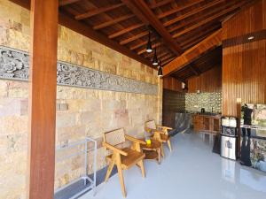 a room with wooden tables and a stone wall at Ubud Paradise Luxury Villa in Ubud