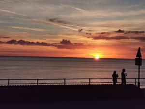 two people standing on a pier watching the sunset at Lovely Seafront 2 bed flat in Aberystwyth in Aberystwyth +9 photos