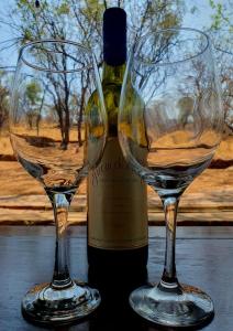 two wine glasses sitting next to a bottle of wine at Rock Cottage, Bela-Bela in Bela-Bela