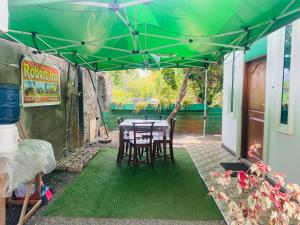 a table and chairs under a green umbrella at Pick Me Village in Dambulla