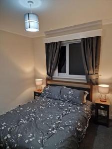 a bedroom with a bed with a window and two lamps at Catalina - Modern 2 bedroom bungalow in Elgin