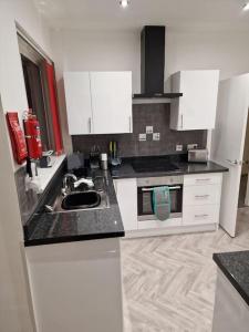 a kitchen with white cabinets and a black counter top at Catalina - Modern 2 bedroom bungalow in Elgin +3 photos
