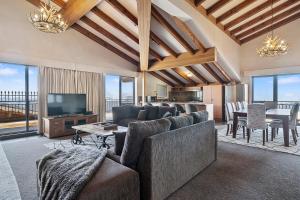 Una sala de estar con un sofá, un televisor y una mesa. en Hotel Pension Grimus, en Mount Buller