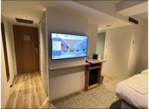 大阪Prince Smart Inn Osaka Yodoyabashi的酒店客房的墙上配有平面电视