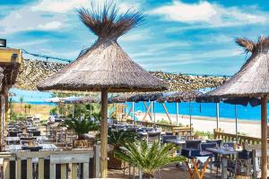a restaurant with tables and straw umbrellas on the beach at Hotel & Restaurant San Pellegrino in Folelli