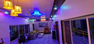 a living room with purple and blue lights on the ceiling at Hotel O Home Bhogwal Farmhouse & Party Zone in Chinchavli