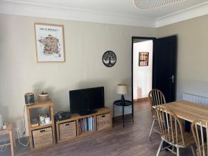 a living room with a table and a television at Maison St Lary 4Ch 10pers jardin in Saint-Lary-Soulan