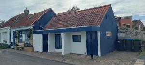 een blauw-wit huis met een rood dak bij Schrijvershuisje - sfeer & stilte Zeeuws Vlaanderen in Zaamslag