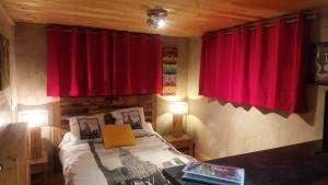 a bedroom with red curtains and a bed with a table at studio des dents de lanfon in Écharvine
