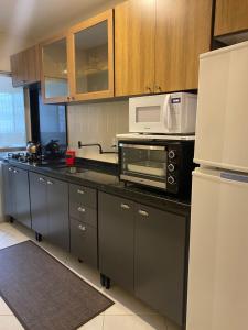 a kitchen with a black counter top with a microwave at Apto a 50m da praia in Balneário Camboriú