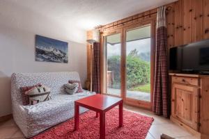 een woonkamer met een bank, een tafel en een raam bij Les Carlines in Les Contamines-Montjoie