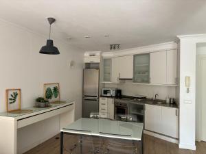 a kitchen with white cabinets and a glass table at La Tejita Paradise in La Tejita
