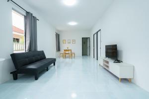 ein Wohnzimmer mit einer schwarzen Couch und einem Fernseher in der Unterkunft ME House Banchang in Ban Chang