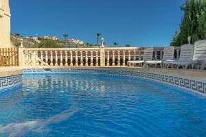 a swimming pool with chairs and a fence at 6 Bedroom Luxury Villa, Jacuzzi & heated pool 18 guests in Mutxamel
