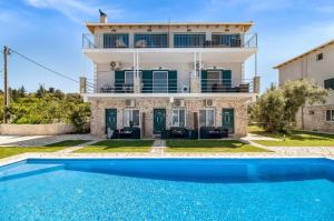 a villa with a swimming pool in front of a house at Gkountis Apartments in Tsoukaladhes