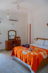 a bedroom with a bed with an orange blanket and a mirror at Akhenaten Apartments in Luxor +43 photos