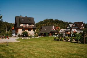 a group of houses in a yard with a green lawn at Tatra House z Jacuzzi in Poronin