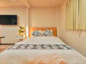 a bedroom with a large white bed and a television at 星野の宿 日本橋黒門道頓堀心斎橋難波エリア中心地 in Osaka