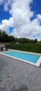 a blue swimming pool with a field in the background at Casa da Igreja-Abadim in Cabeceiras de Basto