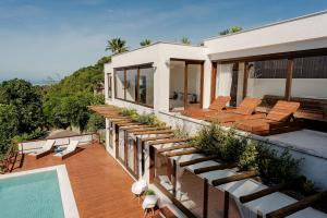 einen Balkon mit Stühlen und einen Pool auf einem Haus in der Unterkunft Casa Blanca - Vista espetacular no coração do Arraial d'Ajuda in Arraial d'Ajuda