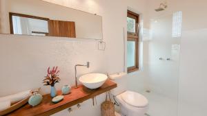 ein Badezimmer mit Waschbecken, Toilette und Spiegel in der Unterkunft Casa Blanca - Vista espetacular no coração do Arraial d'Ajuda in Arraial d'Ajuda + 42 Fotos