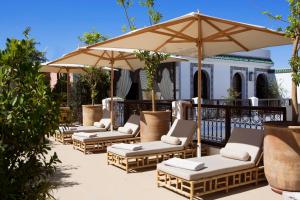 eine Reihe von Stühlen und einem Sonnenschirm auf einer Terrasse in der Unterkunft Riad Dar Alfarah in Marrakesch