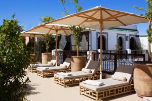 una fila de sillas y una sombrilla en un patio en Riad Dar Alfarah, en Marrakech