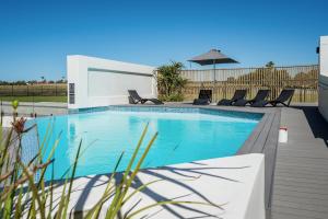 una piscina con sedie e un ombrellone di Boardwalk Bungalow a Gqeberha