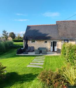a cottage with a patio and grass yard at Golf Open Sport Houses in Saint-Fort