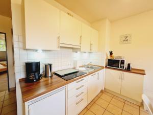 レリクにあるFerienwohnung B6の白いキャビネットとシンクと電子レンジを備えたキッチン