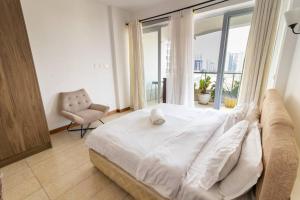a large white bed in a room with a window at Elegant 2 BED apt in Kilimani with balcony views in Nairobi +32 photos