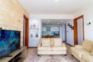 a living room with two white couches and a flat screen tv at Elegant 2 BED apt in Kilimani with balcony views in Nairobi