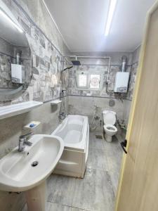 ein Badezimmer mit Waschbecken, Badewanne und Toilette in der Unterkunft Beautiful Old Apartment in Madinat Al Ashir min Ramadan