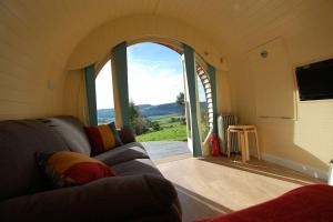 a living room with a couch and a large window at Ty Barcud Glamping Pod in Aberystwyth
