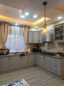 a large kitchen with white cabinets and a window at Serene Homes 01 in Kampala