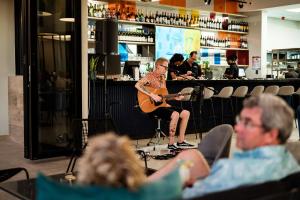 una donna sta suonando la chitarra in un bar di Boardwalk Bungalow a Gqeberha