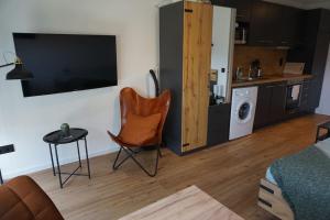 ein Wohnzimmer mit einem Stuhl und einem TV an der Wand in der Unterkunft APART LIVING Sindelfingen near to Daimler in Sindelfingen