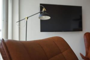 ein Wohnzimmer mit einer Couch, einer Lampe und einem Fernseher in der Unterkunft APART LIVING Sindelfingen near to Daimler in Sindelfingen + 7 Fotos