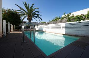 a swimming pool with a fence and a palm tree at Villa Oasi in San Vito lo Capo