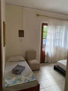 a bedroom with a bed and a chair and a window at Sandras apartment in Igoumenitsa