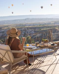 a woman in a hat sitting on a chair at a table at Very Peri Cappadocia - The Lifestyle Luxury Design Hotel in Uchisar +127 photos
